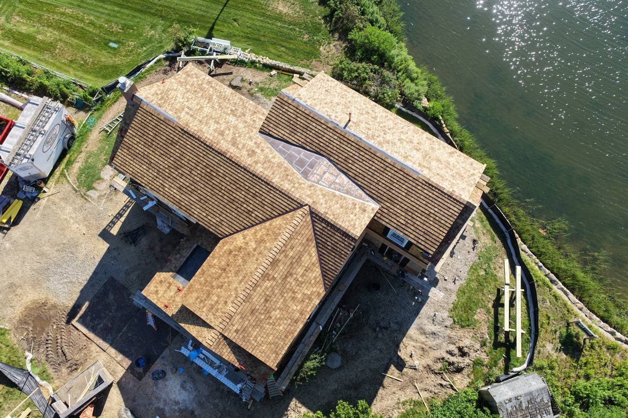 Cedar roof and red copper roof installation with water view in background