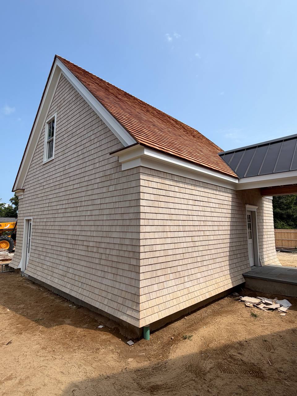 White carriage-style garage doors installed on cedar clad structure