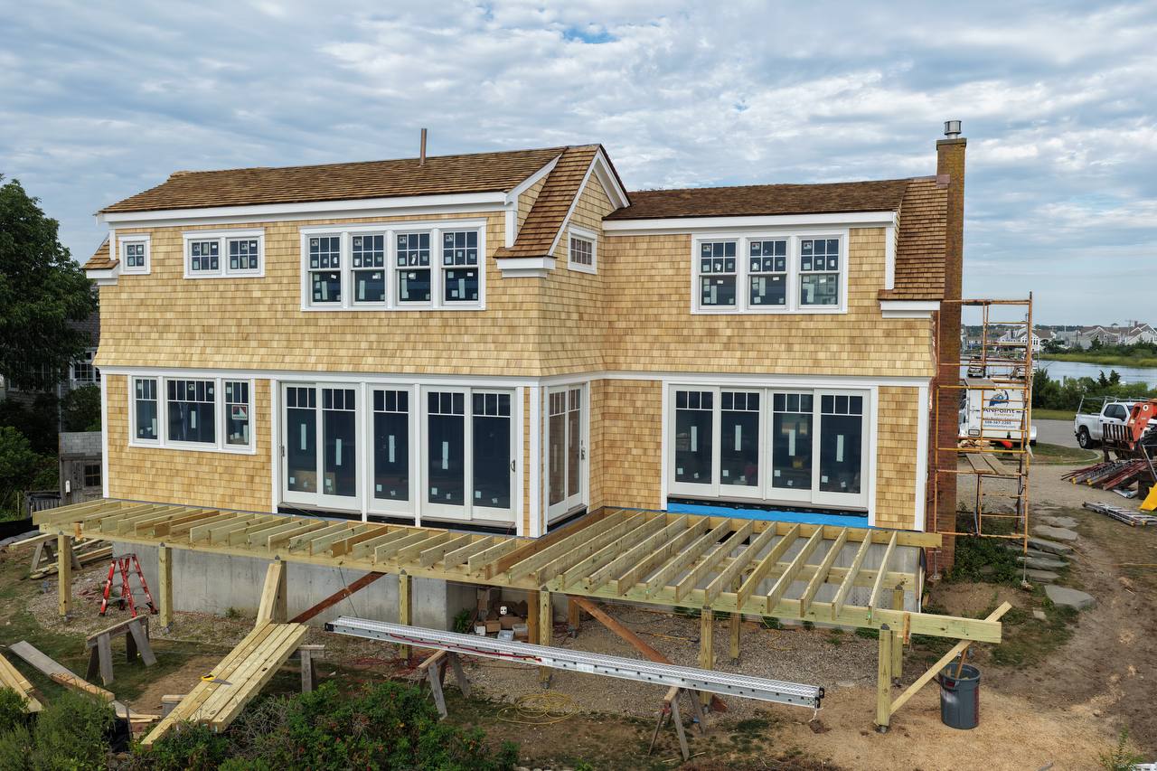 Side elevation showing white cedar siding progress and scaffolding
